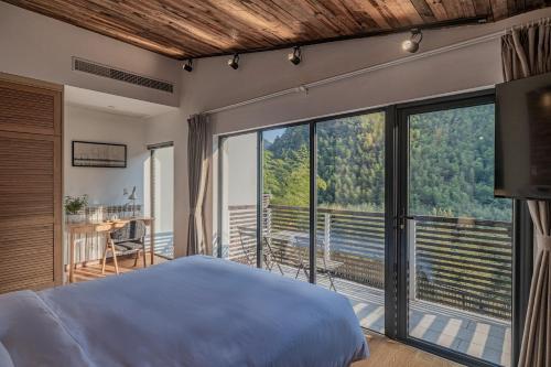 una camera da letto con un letto e una grande finestra di Moganshan Linqiguyin Hotel a Fanjiawu