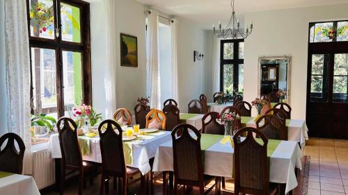 a dining room with white tables and chairs and windows at Gościniec Kowalova in Mieroszów