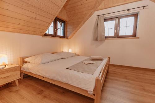 a bedroom with a bed and two windows at Dziewięćsił &Chaber _domki blisko lasu in Grywałd