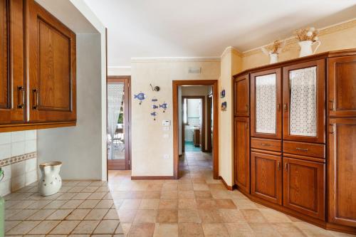 a kitchen with wooden cabinets and a tile floor at Villa Monica by BarbarHouse in Polignano a Mare