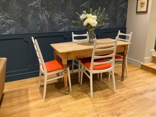 a wooden table with four chairs and a vase with flowers at Fab cottage in the heart of Deal - Great Location in Kent