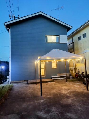 a patio with an umbrella in front of a building at ビーチまで徒歩5分 BBQ無料 7名迄OK 戸建て貸切宿 Bignet villa in Miyamae