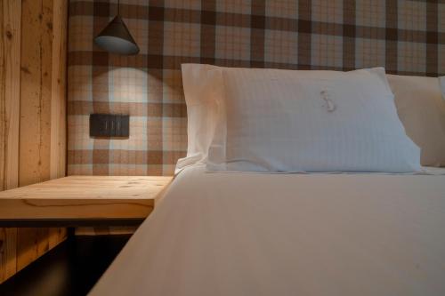 a bed with a white pillow and a wooden table at Hotel San Lorenzo in Bormio