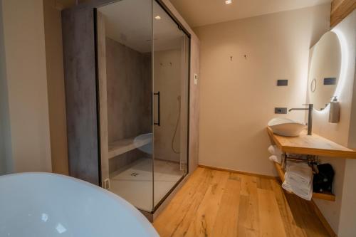 a glass shower in a bathroom with a wooden floor at Hotel San Lorenzo in Bormio