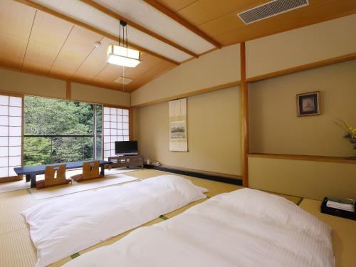 two beds in a room with a tv and a window at 多武峰観光ホテル in Sakurai