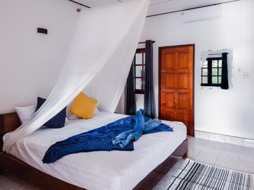 a bed with a blue blanket on it in a room at Burni Houses in Klong Prao Beach