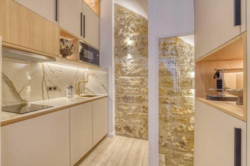 une cuisine avec un évier et un mur en pierre dans l'établissement Central historic loft by architect, near Louvre, à Paris
