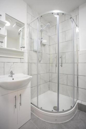 a white bathroom with a shower and a sink at Saint Patrick's District Apartments in Dublin