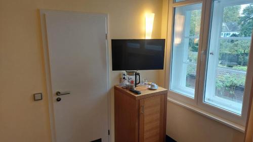 Una habitación con un televisor sobre un mueble con ventanas. en die Villa, Zimmer 23, EZ, en Leverkusen
