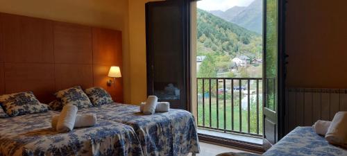 a hotel room with two beds and a large window at Hotel Saurat in Espot