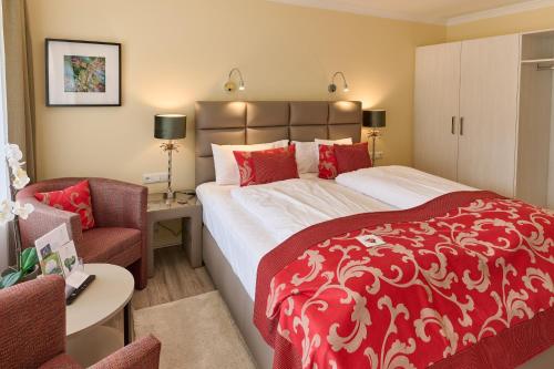a bedroom with a red and white bed and a chair at Landhotel Kallbach - 4 Sterne SUPERIOR in Hürtgenwald