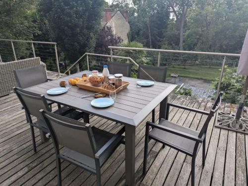 a wooden table with chairs on a deck at Au Bonheur des Voyageurs, 30' de Paris in Villennes-sur-Seine