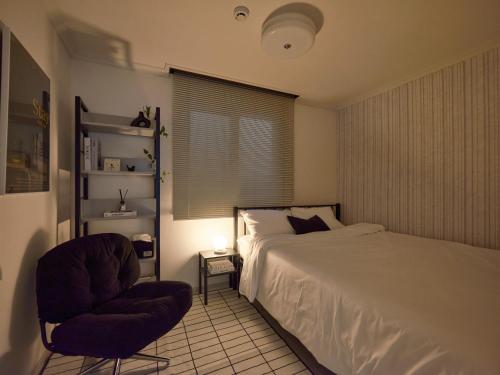 a bedroom with a bed and a chair and a window at joyfulstay in Seoul