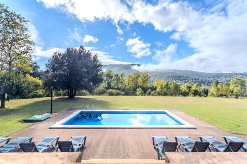 an outdoor swimming pool with chairs and a lawn at Can Mestrehumà in Bas