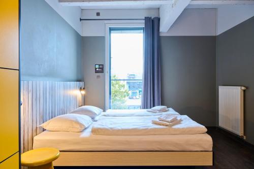 a bedroom with a large bed with a window at MEININGER Hotels Bruxelles City Center in Brussels