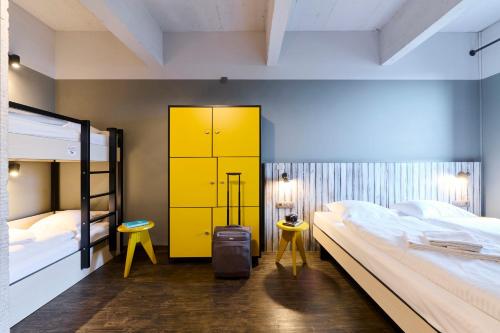 a bedroom with two bunk beds and a yellow cabinet at MEININGER Hotels Bruxelles City Center in Brussels