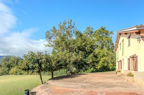 a house with a tree next to a driveway at Can Mestrehumà in Bas