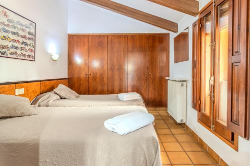 two beds in a room with wooden walls at Can Mestrehumà in Bas