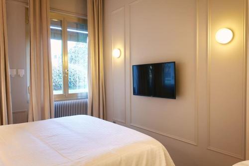 une chambre avec un lit et une télévision sur un mur dans l'établissement Hermes Room - Duke Housing, à Paris
