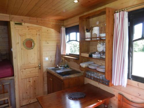 a kitchen in a log cabin with a sink and a table at Les Roulottes de la Risle in Calleville