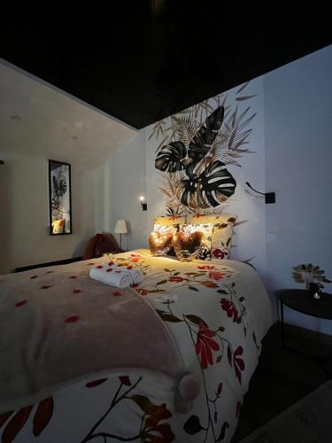 a bedroom with a bed with a floral bedspread at Love room avec spa privé in Le Perrier