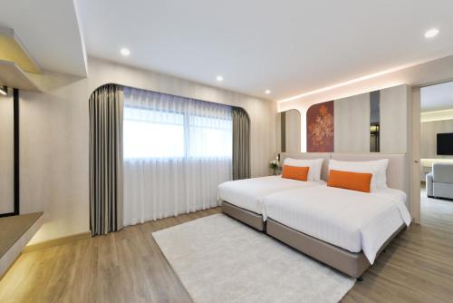 a bedroom with a large white bed with orange pillows at Centre Point Plus Hotel Pratunam in Bangkok