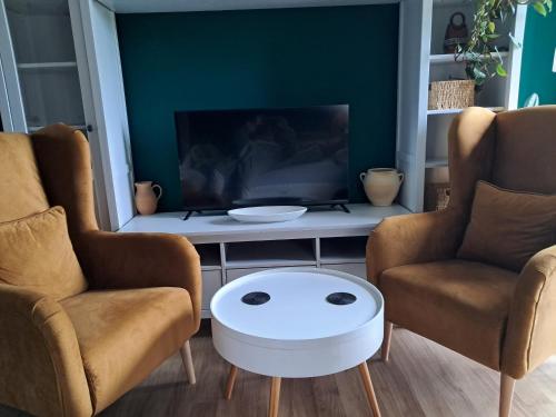 a living room with two chairs and a tv at Dom z Sauną i Jacuzzi- na wyłączność lub pokoje in Serock