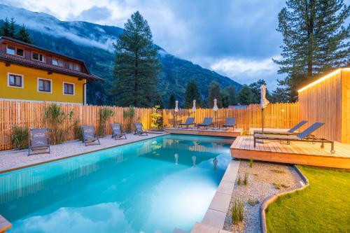 a swimming pool with chairs and a wooden fence at AlpinSpa zur Post Apartment - Bergbahn im Sommer 2025 inklusive in Bad Gastein