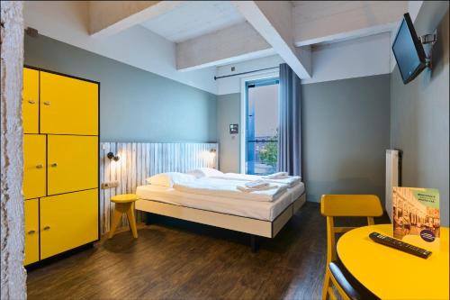 a bedroom with a bed and a desk and a tv at MEININGER Hotels Bruxelles City Center in Brussels
