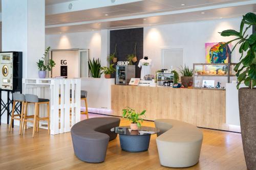 a restaurant with stools and a counter with plants at INNSiDE by Meliá Aachen in Aachen