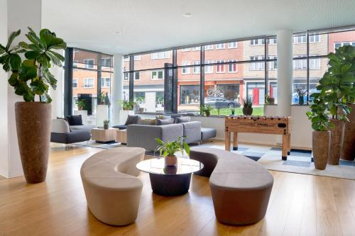 a living room with couches and a table with plants at INNSiDE by Meliá Aachen in Aachen