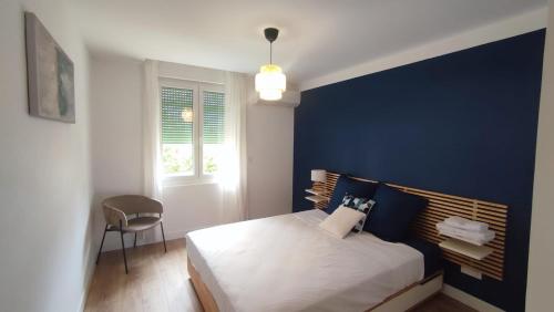 une chambre avec un lit avec un mur bleu dans l'établissement Le Victor Hugo - Avignon intra muros - Calme - Clim - Lumineux, à Avignon
