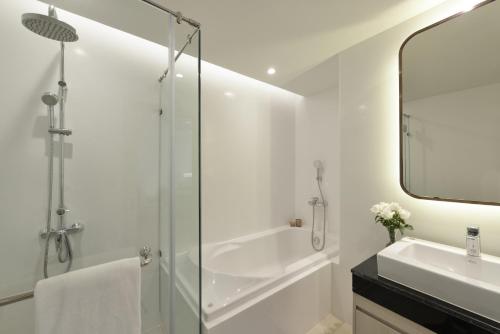 a bathroom with a glass shower and a sink at Centre Point Plus Hotel Pratunam in Bangkok