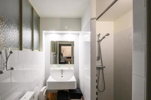 a white bathroom with a sink and a shower at L'Apouticayre in Montaut