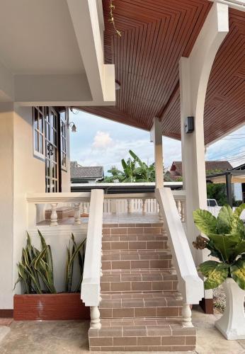 a staircase leading up to a house with a wooden ceiling at 97 Light House Songkhla in Songkhla