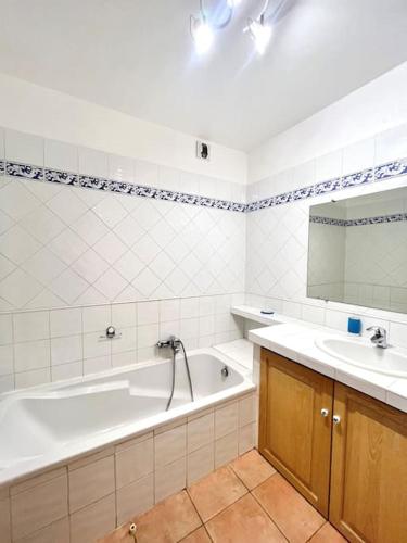 une salle de bain blanche avec une baignoire et un lavabo dans l'établissement Appartement vue mer avec piscine, à LʼÎle-Rousse