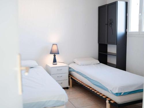 - une chambre avec deux lits, une armoire et une lampe dans l'établissement Pavillon 3 pièces, 6 pers, vue mer, clim, animaux, parking - FR-1-409-101, à Fleury
