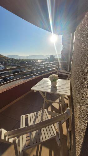 a table and a bench on a balcony with the sunshine at Los Andes familiar y tranquilo in Los Andes