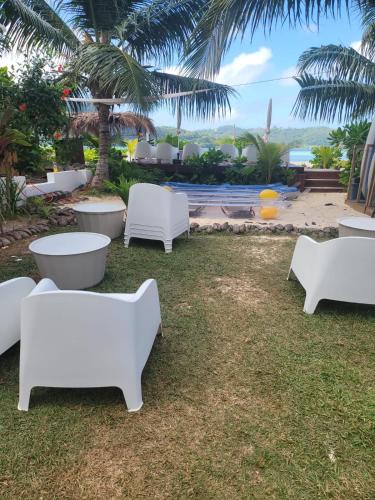 a group of white chairs and tables on the grass at Sunset View Self Catering in Anse Boileau