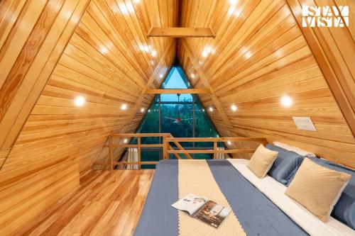 a bed in a wooden room with a large window at StayVista at Rahat with Private Pool, Lawn & BBQ in Srinagar
