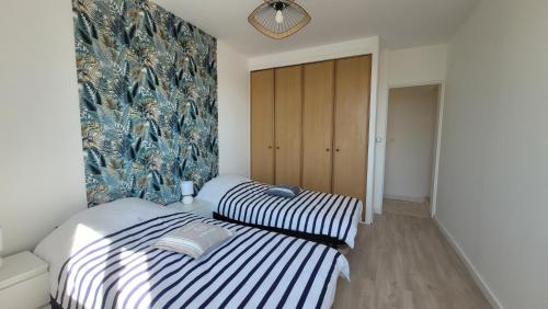 deux lits côte à côte dans une pièce dans l'établissement Le Marquis, à Saint-Sulpice-de-Royan