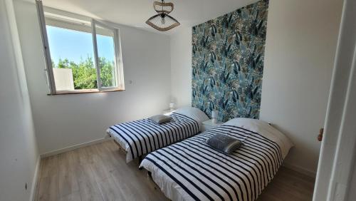 deux lits dans une chambre avec une fenêtre dans l'établissement Le Marquis, à Saint-Sulpice-de-Royan