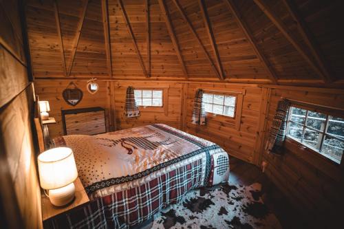 ein Schlafzimmer mit einem Bett in einer Holzhütte in der Unterkunft Le Kota Montagne in Les Poulières