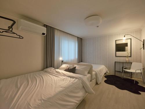 a hotel room with two beds and a chair at joyfulstay in Seoul