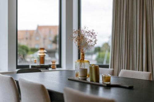 a dining room table with a vase of flowers and chairs at Huswell - Luxury Villa for 8 Guests Near the Beach in Knokke in Knokke-Heist