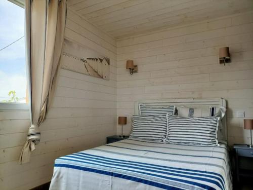 a bedroom with a bed with blue and white stripes at CHALET la Perle de Gruissan in Gruissan