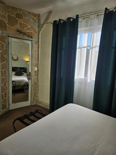 a bedroom with a bed with blue curtains and a window at Logis Hôtel restaurant Chez Jeannette in Fixin