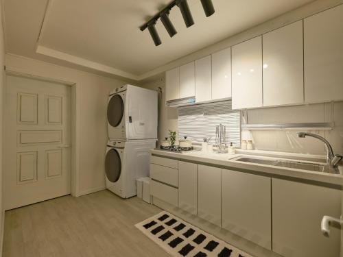 a kitchen with white cabinets and a white refrigerator at joyfulstay in Seoul