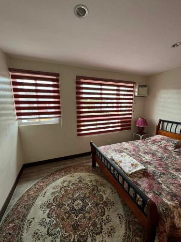 sypialnia z dwoma oknami, łóżkiem i dywanem w obiekcie bendetto residences w mieście Manila