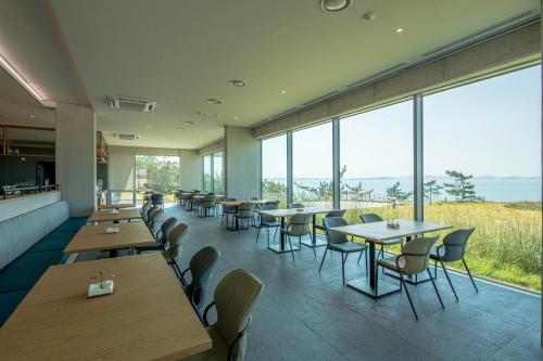 a restaurant with tables and chairs and large windows at Haenam 126 Hotel in Haenam